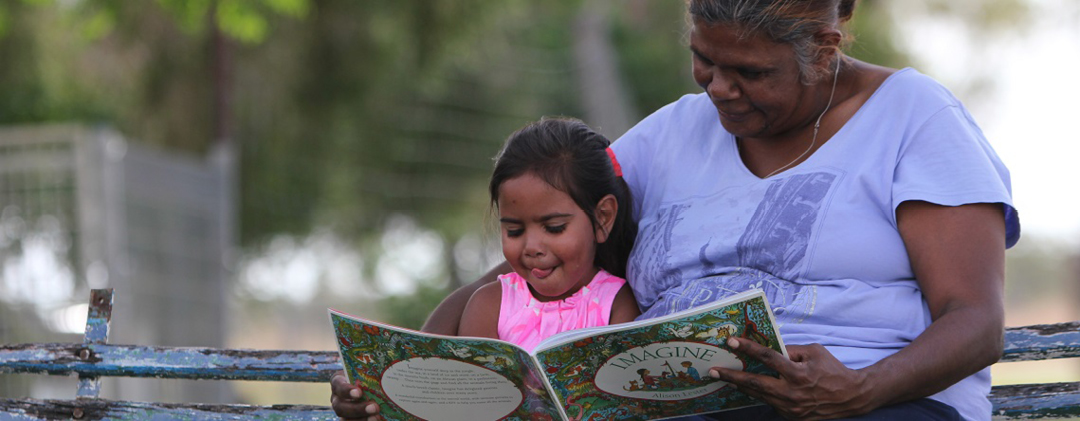 Photograph of an Aboriginal woman reading to a child