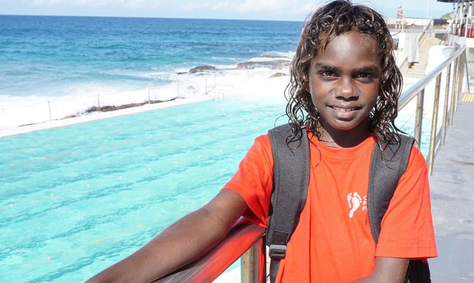 Photograph of an Indigenous youth by an ocean-side pool