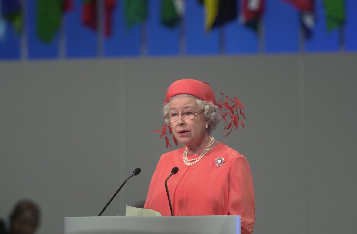 Her Majesty The Queen stands behind a lectern