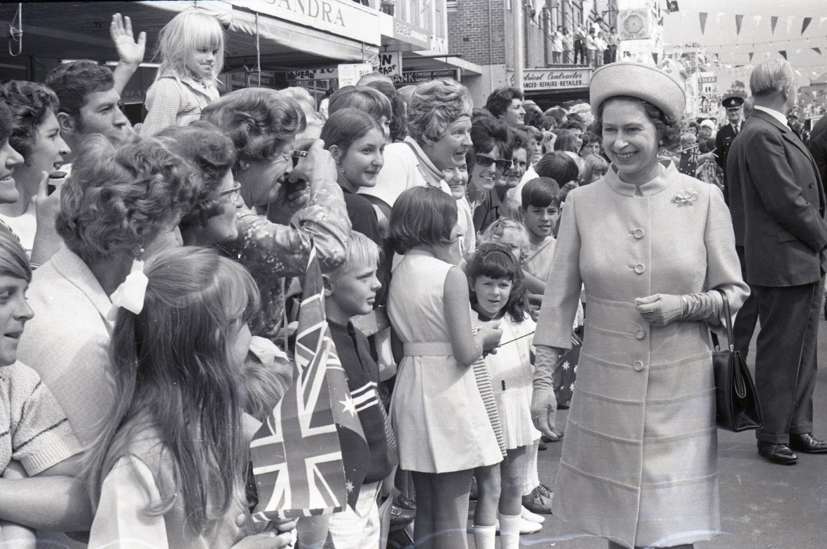 Black and white photo of Her Majesty The Queen greeting well-wishers lining a Wollongong street