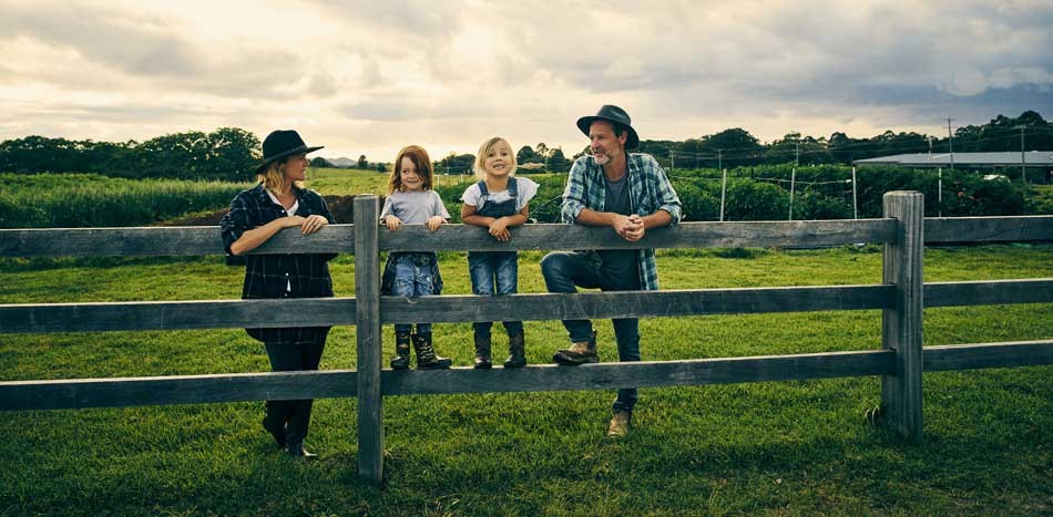 A farming family hanging out on a fence