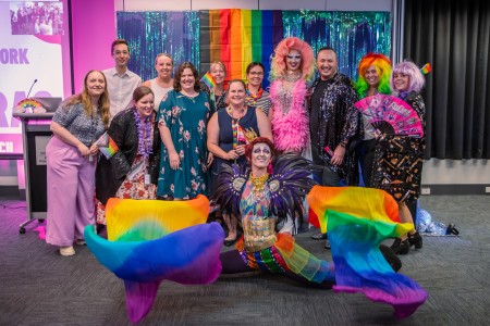 A group of people in bright clothing at a PM&C Mardi Gras event.