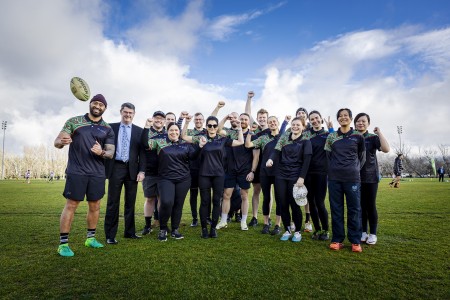 A group of people in sportswear holding footballs at the NAIDOC week touch footy carnival.