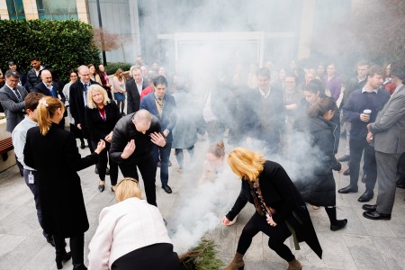 A group of people performing a smoking ceremony during a PM&C Naidoc Week event.