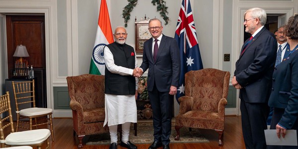 Prime Minister Anthony Albanese shaking hands with Prime Minister Narendra Modi of India in front of the flags of Australia and India.