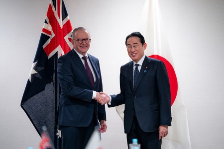 Prime Minister Anthony Albanese shaking hands with Prime Minister Kishida Fumio of Japan in front of the flags of Australia and Japan.