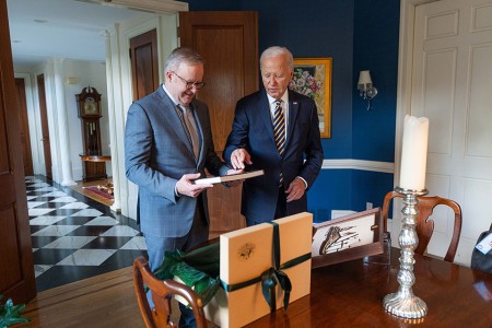 Prime Minister Anthony Albanese with President of the United States Joseph R. Biden Jr. looking at a book in front of a gift box with a bow on it.