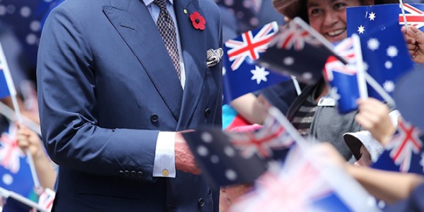 Charles, Prince of Wales greeting a large crowd of people that are holding Australia flags.