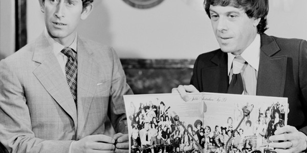 Black and white photograph of Charles, Prince of Wales seated with Molly Meldrum on the set of television show Countdown looking at an open record cover.