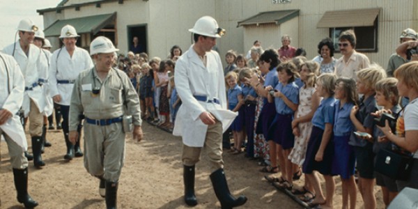 Charles, Prince of Wales, wearing a white coat and a hard hat fitted with a mining lamp, is greeted by a line of schoolchildren during a visit to the Mount Charlotte Gold Mine on the edge of Kalgoorlie.