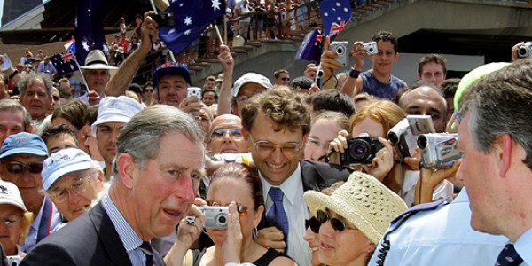 A large crowd of people on the steps in front of Sydney Opera House holding Australia flags, greeting Charles, Prince of Wales.