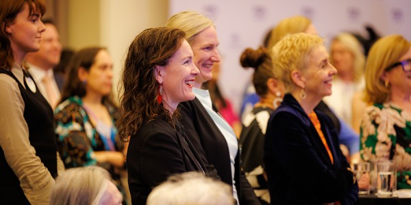 Tessa Boyd-Caine and Micaela Cronin listen to a speech being given at an event to mark the 50th anniversary of the Office for Women.