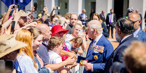 His Majesty greets a throng of cheerful well-wishers on the other side of a small barricade.