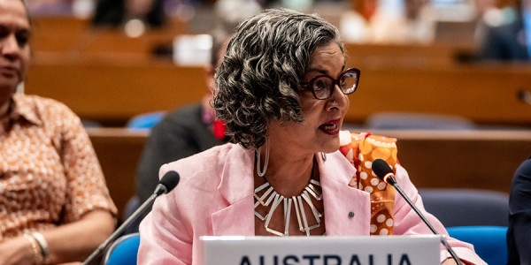 Australia’s Head of Delegation, Ms Padma Raman PSM, seated behind a microphone with a sign in front that says Australia.