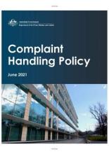 Tile with text on a blue background at the top. At the bottom is a building with sky above and trees at right. The text is: Complaint Handling Policy.