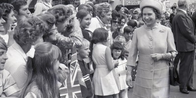 Black and white photo of Her Majesty The Queen greeting well-wishers lining a Wollongong street