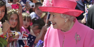 Her Majesty The Queen wearing a pink hat and jacket as she greets a crowd