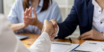 Two people (managers and job applicants) shake hands after a job interview, while another person claps in the background